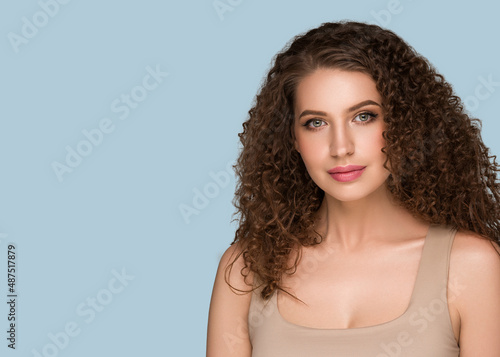 Curly long brunette hair woman beauty portrait, female glamour face. Color backgound blue