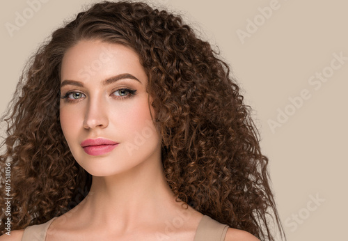 Curly long brunette hair woman beauty portrait, female glamour face. Color backgound brown