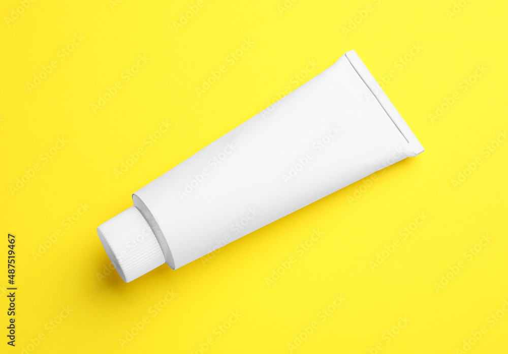 Blank white tube of ointment on yellow background, top view. Space for text Blank white tube of ointment on yellow background, top view. Space for text