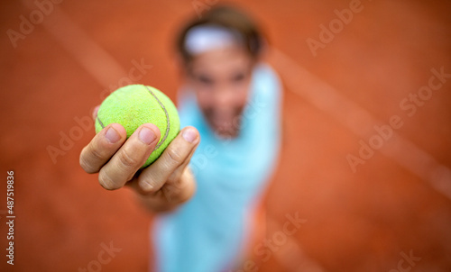 Young handsome tennis player with racket and ball prepares to serve at beginning of game or match.