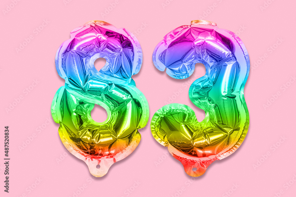 Rainbow foil balloon number, digit eighty three on a pink background. Birthday greeting card with inscription 83. Top view. Numerical digit. Celebration event, template. Rainbow foil balloon number, digit eighty three on a pink background. Birthday greeting card with inscription 83. Top view. Numerical digit. Celebration event, template.
