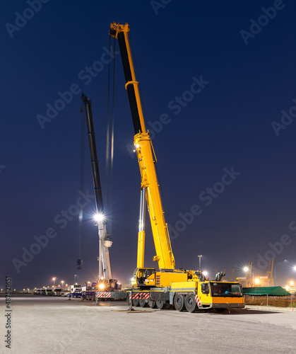 Two mobile cranes are waiting to lift large cargos at the port. photo