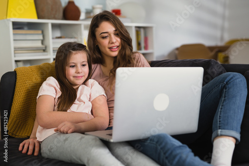 mother and daughter relaxing at home and using laptop computer