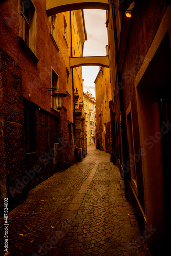 Gloomy narrow long antique street with a stone path in europe. Beautiful old architecture.