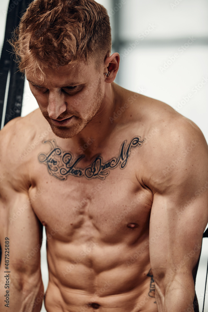Obraz premium Portrait handsome and confident young Caucasian man at gym background. Face of brutal muscular sexy male. He's sweating after fitness workout. healthy and lifestyle athletic people. copy space