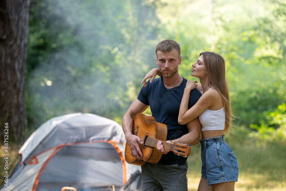 Romantic couple camping on spring landscape, man with guitar. Adventure for young lovers campers on nature. Hiking couple in love.