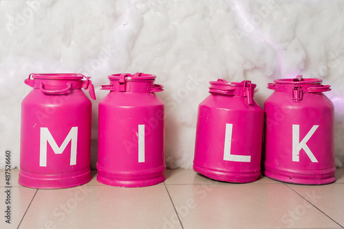 Vintage pink storage containers milk on white background. Metal milk churns stand in row photo