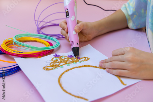 The child draws a 3D printing pen.