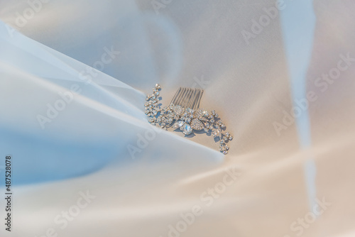 a wedding comb for decorating a hairstyle made of precious stones lies on a snow-white veil