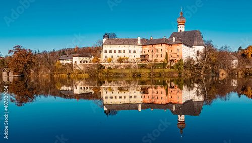 Beautiful indian summer view with reflections and a monastery at the famous Hoeglwoerther See lake, Bavaria, Germany