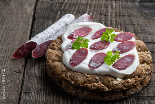 Crispbread with cream cheese and salami on wooden table