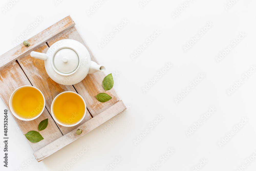 Tea drinking with white teapot and black tea in two cups Tea drinking with white teapot and black tea in two cups