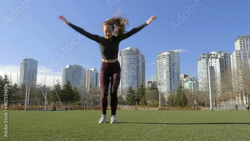 Fit young woman doing burpees bodyweight exercise in park photo