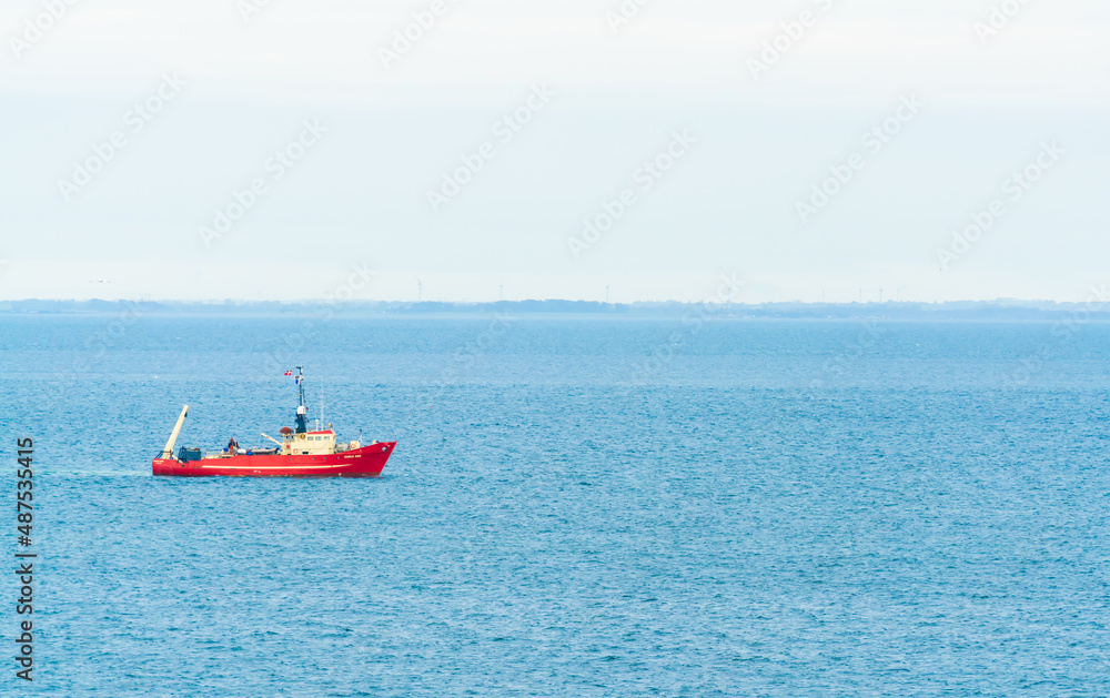 Red ship or working boat at anchor in the Øresund Strait.