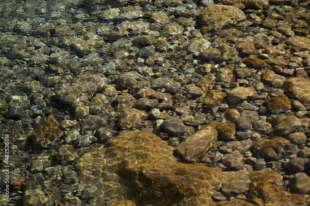 Ripples and sunlight reflexes in a large rock pool filled with pebbles Ripples and sunlight reflexes in a large rock pool filled with pebbles