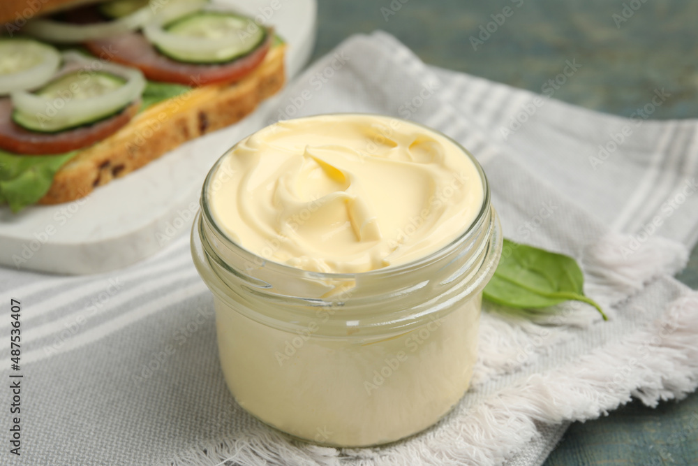 Jar of delicious mayonnaise and napkin on light blue wooden table Jar of delicious mayonnaise and napkin on light blue wooden table