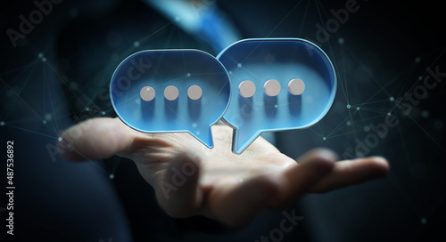 Businessman in dark using digital speech bubbles talk icons. Minimal conversation or social media messages floating over user hand. 3D rendering
