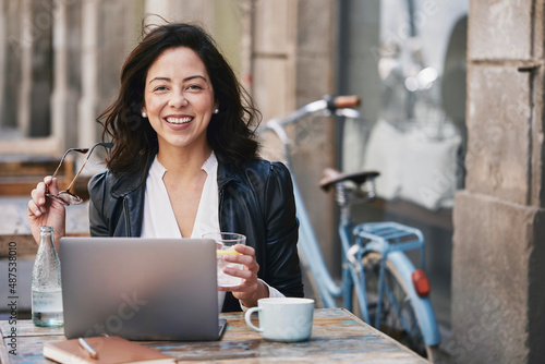 Young woman teleworking on a terrace of a bar with her laptop