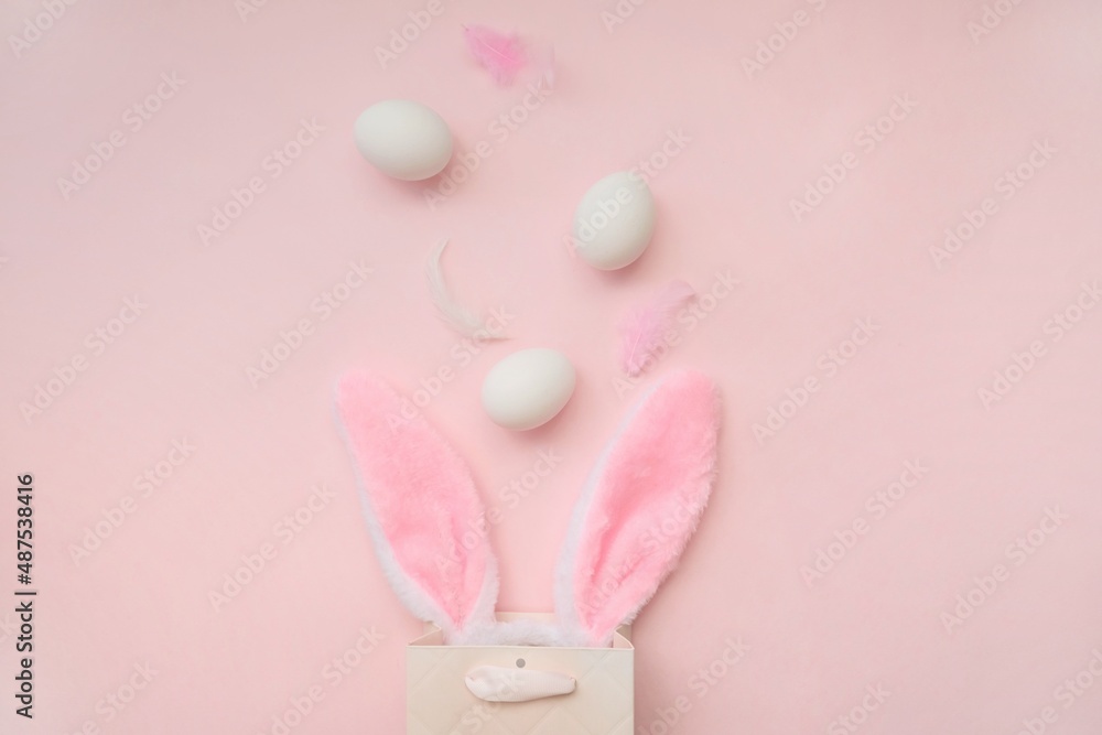 Pink bag, bunny headband and willow branches on a pink background.The concept of Easter, shopping for Easter. Pink bag, bunny headband and willow branches on a pink background.The concept of Easter, shopping for Easter.