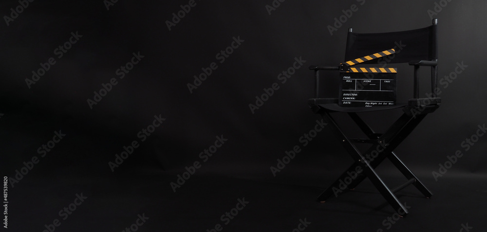 Obraz premium Black director chair. Yellow and black color Clapper board or movie slate on a chair with a black background.