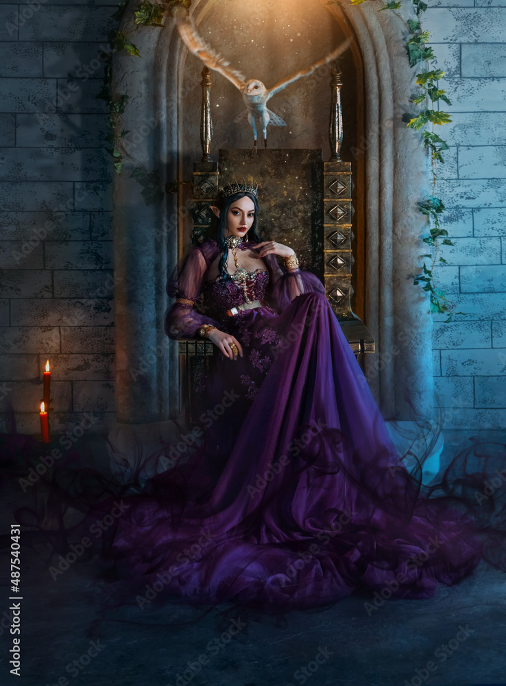 Art photo fantasy woman evil elven queen sits on throne, dark magic around purple long dress. Sexy witch elf girl, pointy ears. Gothic Brunette vampire princess, golden crown. Barn owl flutters wings