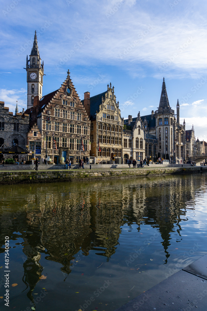 Panoramic of Ghent next to the water channels, with the reflection of the buildings in the water, on a sunny day.