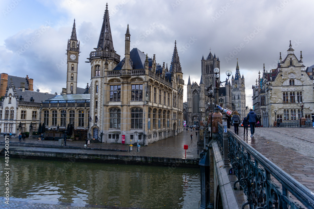 Panoramic of Ghent next to the water channels, from the bridge, with a view of the Ghent church on a cloudy and gray day.