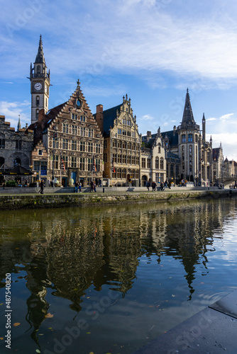 Panoramic of Ghent next to the water channels, with the reflection of the buildings in the water, on a sunny day.
