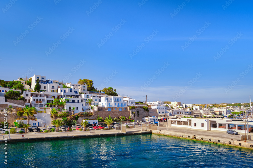Beautiful summer day of Greek island town by seafront. Whitewashed houses by waterfront. Mediterranean vacations. Milos, Cyclades, Greece.