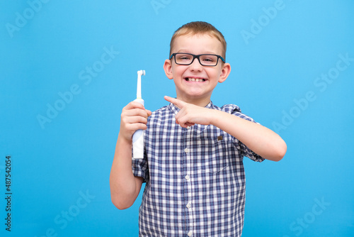 the boy is brushing his teeth. A small child with a toothbrush on a blue background