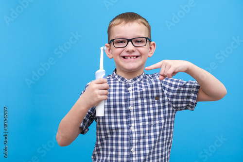 the boy is brushing his teeth. A small child with a toothbrush on a blue background