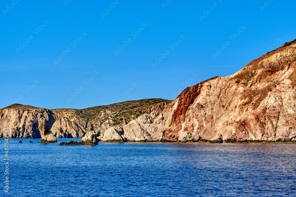Beautiful view of high hill slope of island in Mediterranean Sea. Blue waters, clear blue sky, bright sunshine, summer day, rocks and islets