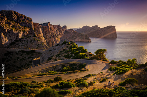Serpentine at sunset with the couple sitting beside the road. Lighthouse of Cap de Formentor (Spain)
