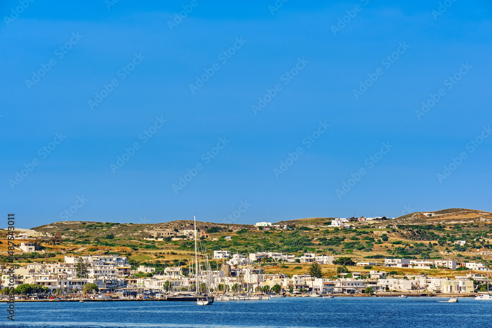 Beautiful sunny summer day in typical landscape of Greek island. Whitewashed houses on hills and by waterfront. Mediterranean lifestyle, vacations.