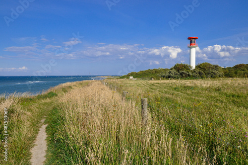 Am Strand und der Steilküste von Heiligenhafen an der Ostsee. Im Hintergrund der Leuchtturm. 