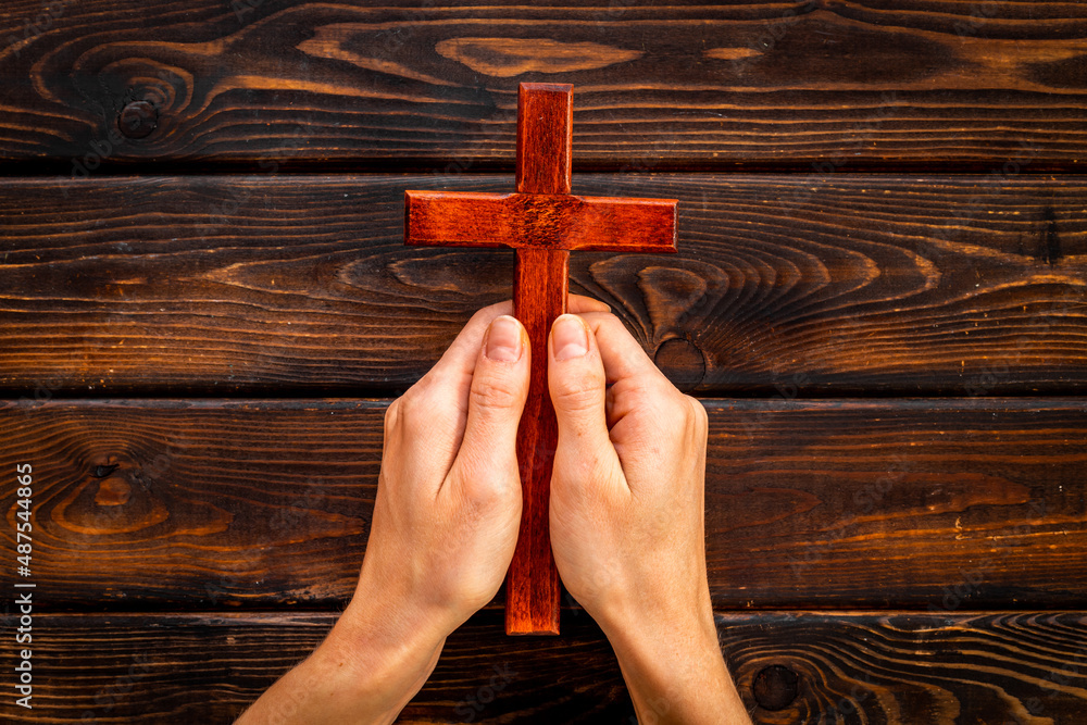 Hands holding christian wooden cross. Faith and prayer concept