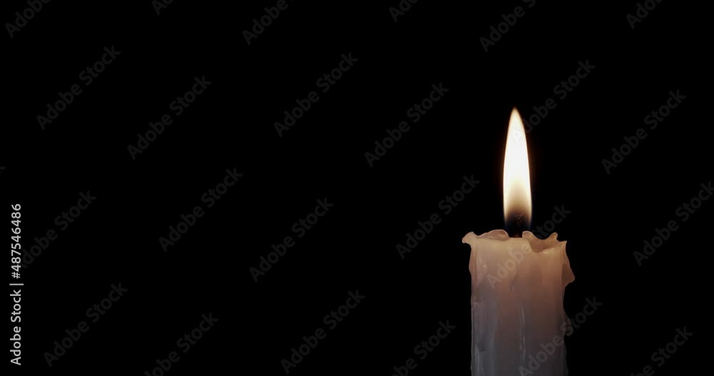 A single white candle burning.Isolated candle burning with dark background.White paraffin candle with yellow shades burns on a black background.Background or illustration of remembrance or celebration A single white candle burning.Isolated candle burning with dark background.White paraffin candle with yellow shades burns on a black background.Background or illustration of remembrance or celebration