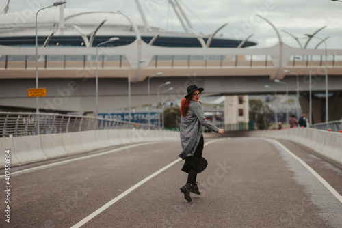 young woman with red hair jumping and running on the road