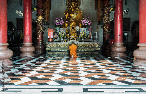 A buddhist Monk is worshiping and praying pay respect in front of the Golden buddha statue inside the Wat Bhoman Khunaram (Bhoman Khunaram Temple). Worship pray meditate to calm the mind,  photo