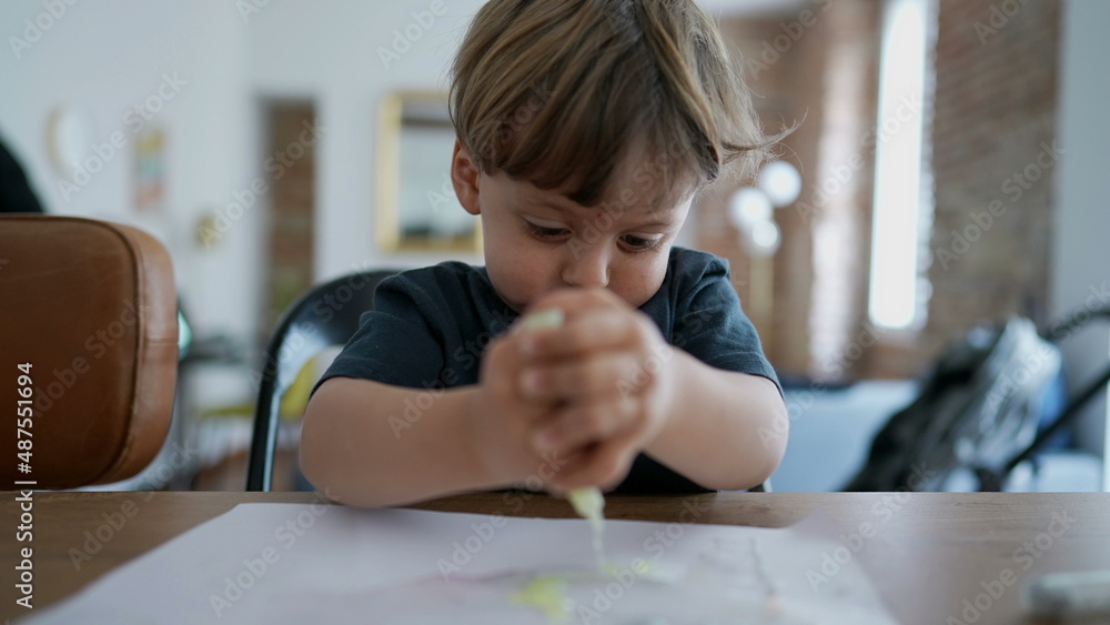 Child playing with art craft at home pressing paint into paper