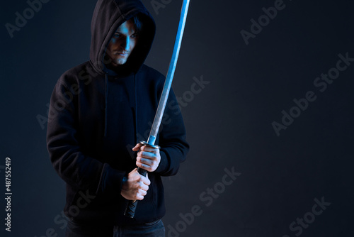 Anonymous with a sword in hand. Dangerous hacker. Internet, cyber crime, cyber attack, system, game, breaking and malware concept. Dark background.