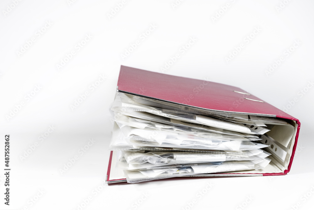 Red ring binder full of transparent punched pockets with receipts, office accounting concept, light gray background, copy space, selected focus Red ring binder full of transparent punched pockets with receipts, office accounting concept, light gray background, copy space, selected focus