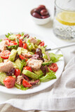 Salad with tuna, lettuce, cucumbers, tomatoes, olives and avocados in white plate on the table