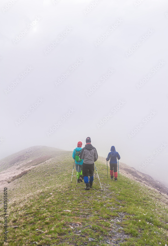 Group of Tourists hiker walking in fog on the top of mountain