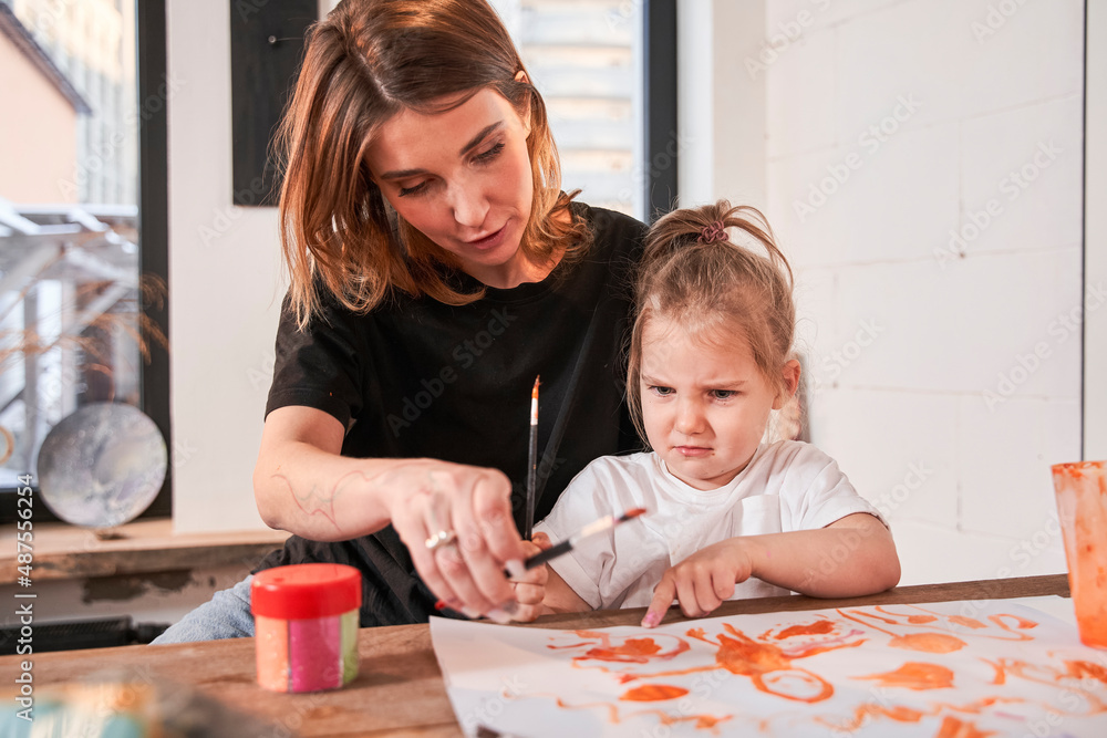 Fototapeta premium Girl feeling dissatisfied while drawing with her teacher during the art lesson