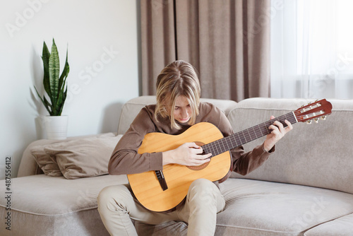 Handsome young guy hold acoustic instrumental guitar playing song