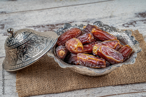 close up picture of dates palm fruit in cup on wooden table background. Dates palm fruit dry is snack healthy.