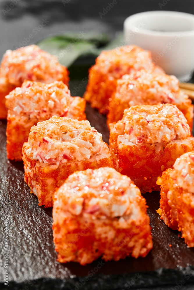 Baked Maki sushi on dark slate. Hot california maki with crab. Sushi roll  with masago outside,