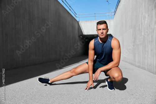 fitness, sport and healthy lifestyle concept - man exercising and stretching leg outdoors