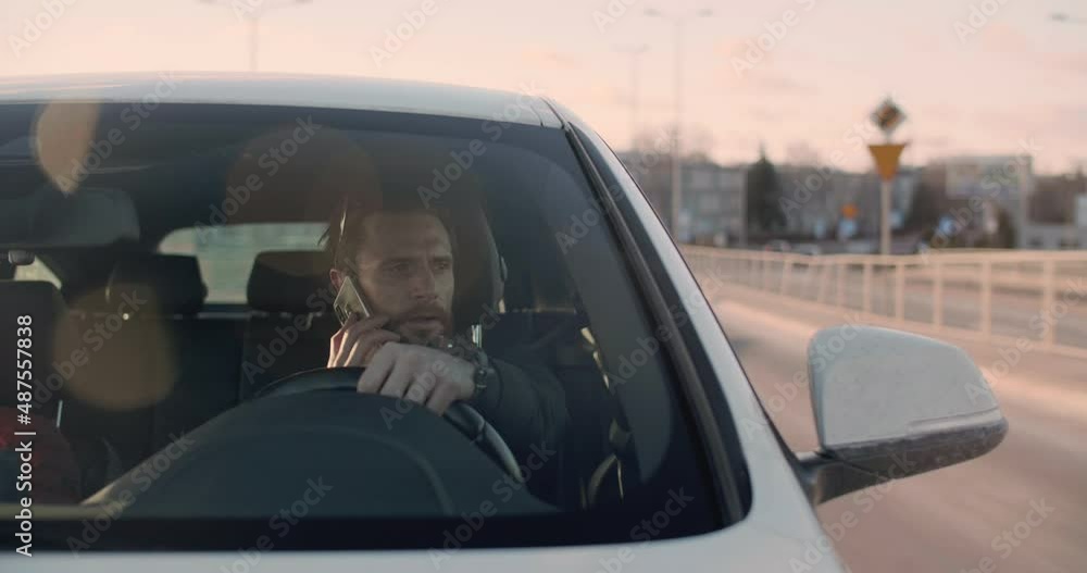 Man driving and talking on the phone in Warsaw on a sunny day Man driving and talking on the phone in Warsaw on a sunny day